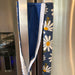 Stylish blue appliance handle covers featuring white and yellow daisies, showing blue backing for modern décor and protection