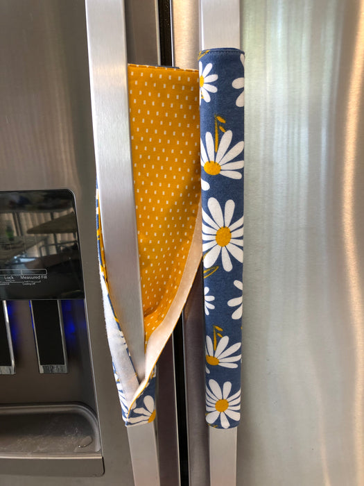 Stylish blue appliance handle covers featuring white and yellow daisies, showing yellow backing for modern décor and protection