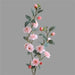 artificial camellia stem with pink flowers and green leaves on a gray background
