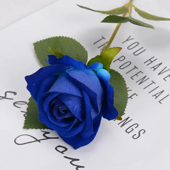 Artificial real-touch rose flower stems in vibrant blue with green leaves on white background.