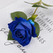 Artificial real-touch rose flower stems in vibrant blue with green leaves on white background.