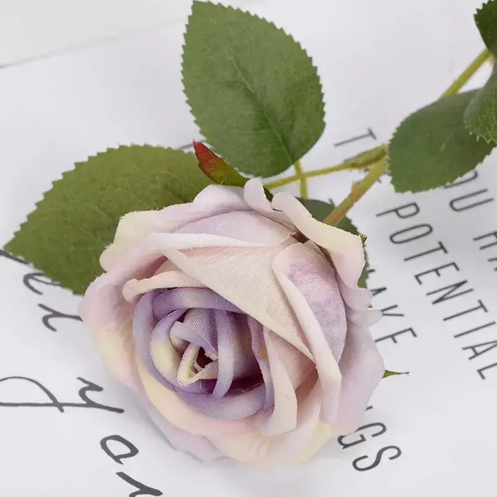Artificial real-touch rose flower stems in soft lavender with green leaves on white background.