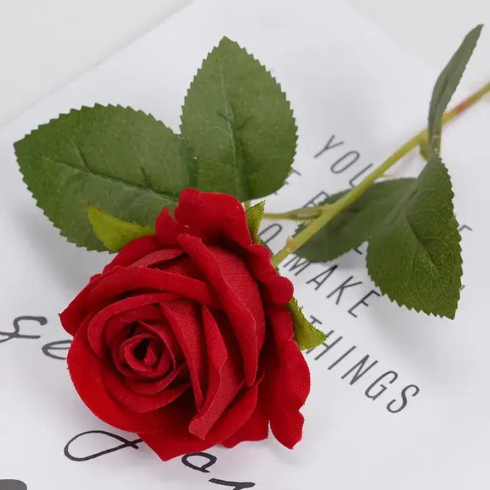 Artificial real-touch rose flower stems with vibrant red blooms and lush green leaves on a white surface.