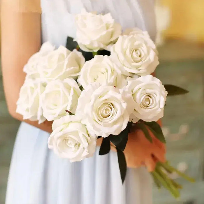 Artificial real-touch rose flower stems bouquet held by a person, showcasing lifelike white roses and lush green leaves.