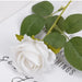 Artificial real-touch rose flower stems with white bloom and green leaves on a decorative surface.