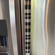 Stainless steel refrigerator with a black-and-cream checkered handle cover.