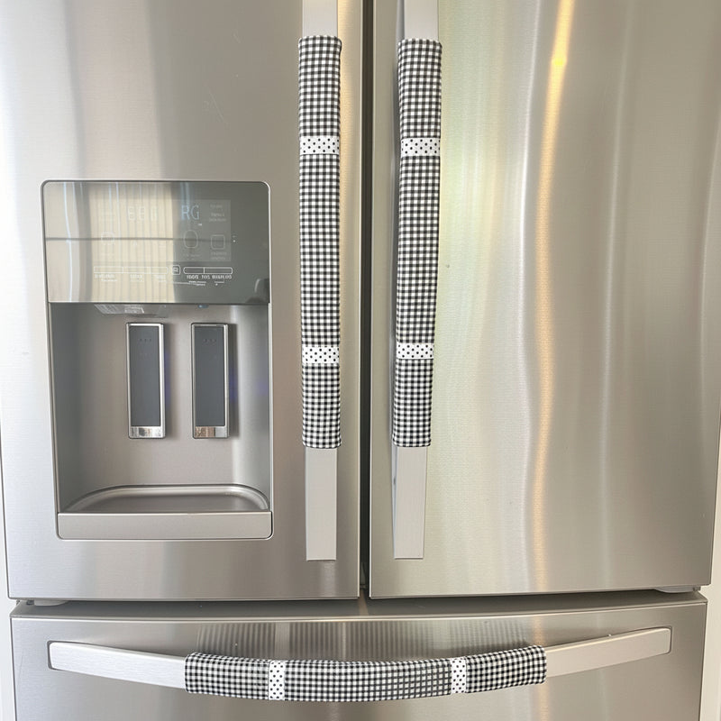 Buffalo plaid appliance handle covers in black and white on a stainless steel refrigerator.
