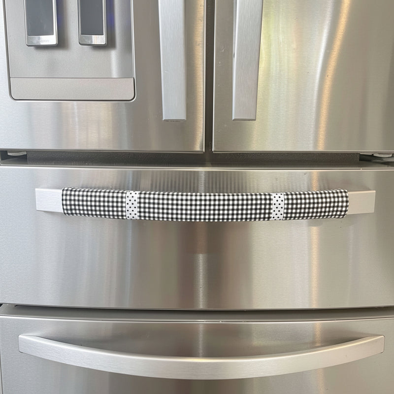 Buffalo plaid appliance handle covers on a stainless steel refrigerator, enhancing kitchen aesthetics with black and white design.