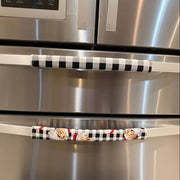 Stainless steel refrigerator with black-and-white checkered and Santa face character door handles.