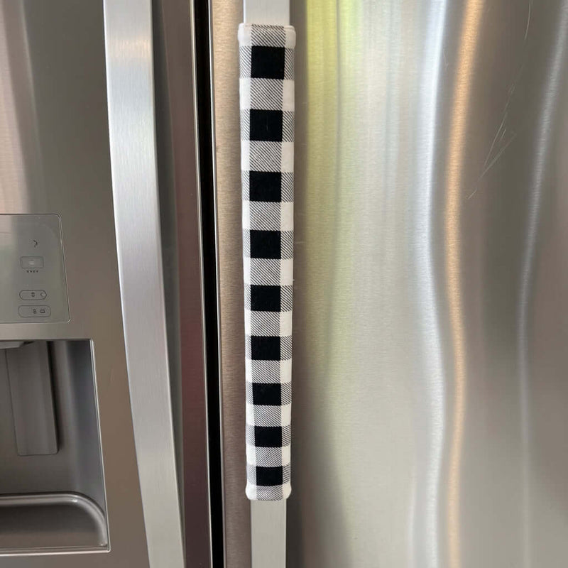 Black and white checkered handle cover on a stainless steel refrigerator door.
