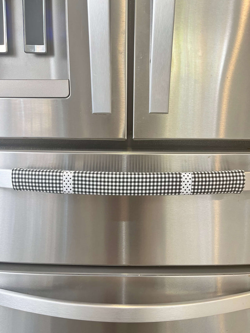 Buffalo plaid appliance handle covers on a stainless steel refrigerator, enhancing kitchen aesthetics with black and white design.