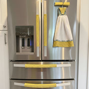 Handmade cute puppy print kitchen hand towel hanging on a stainless steel fridge with yellow decorative accents.