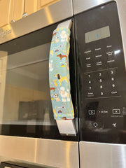 Cute puppy print on appliance handle covers displayed on a microwave, adding charm to the kitchen decor.