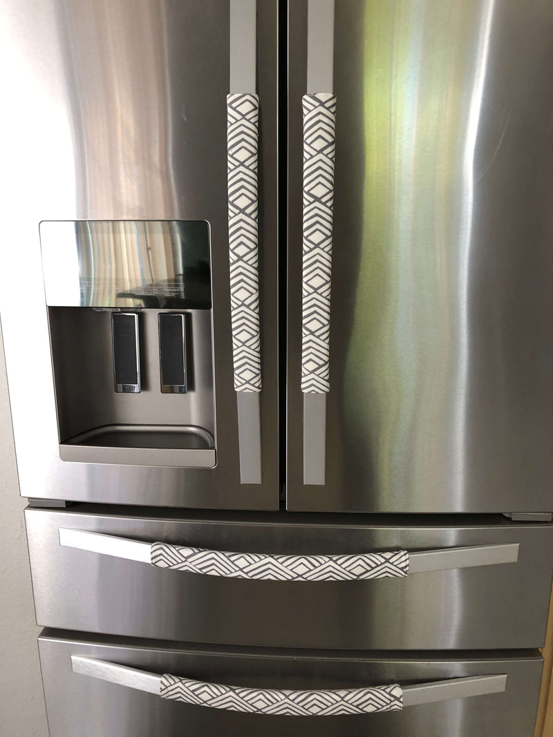 Geometric refrigerator handle covers in grey and white on a stainless steel refrigerator, adding style and functionality.