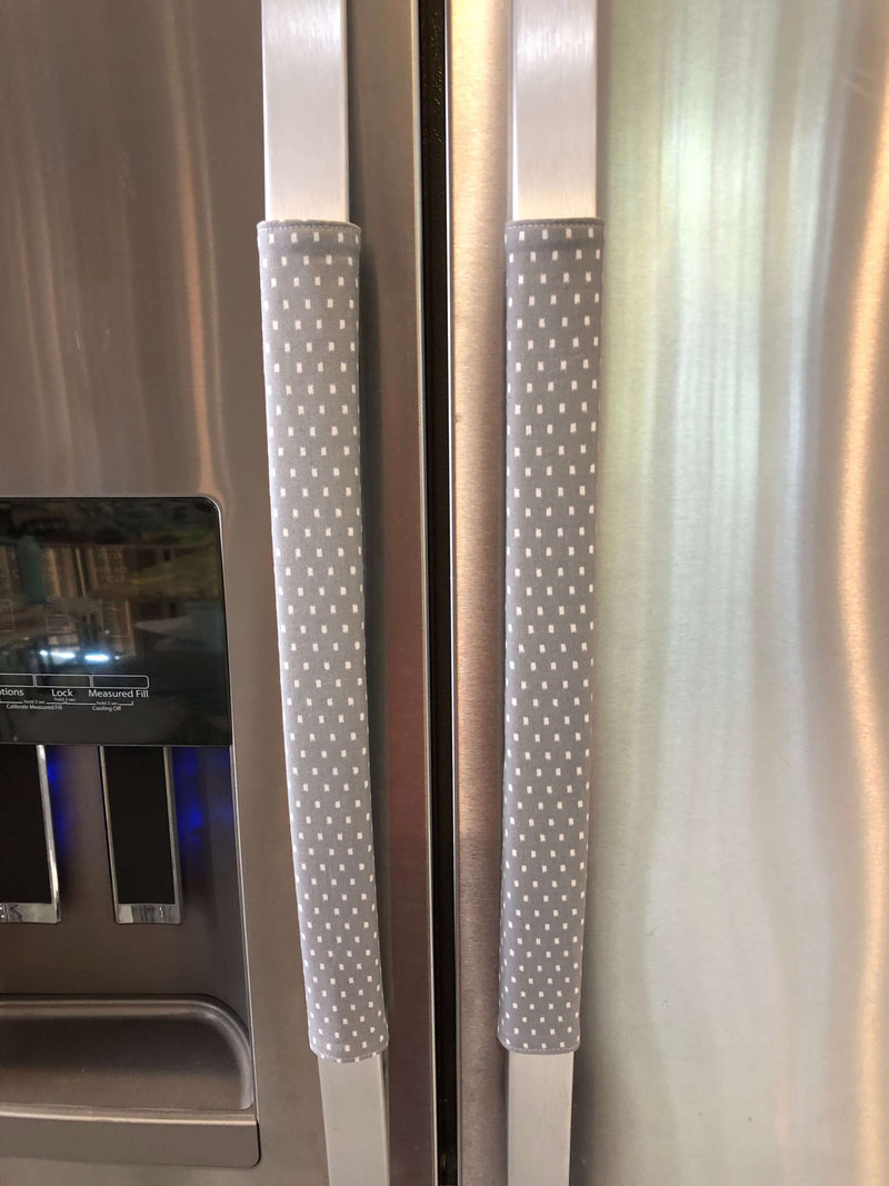 Grey and white gerbera daisy handle covers on stainless steel refrigerator handles.