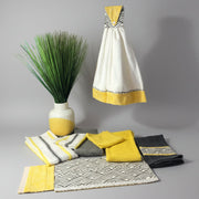 Grey yellow and white ceramic vase featuring decorative textiles and kitchen towels for modern home decor.