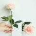 Latex real-touch artificial rose stems held in hand with realistic pink petals and green leaves.