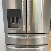 Stainless steel refrigerator with light grey handle covers.