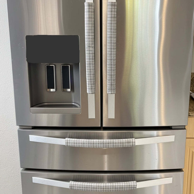 Stainless steel refrigerator with light grey handle covers.