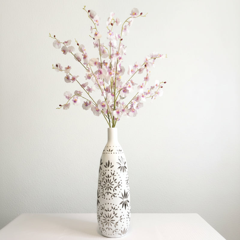 Decorative vase with dancing lady orchid floral branches against a gray wall