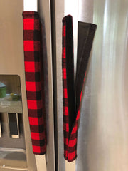 Red and black buffalo check appliance handle covers on stainless steel fridge, adding rustic charm and protection.