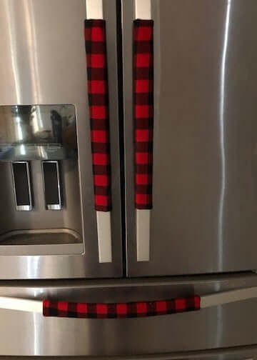 Red and black buffalo check appliance handle covers on a refrigerator door for rustic kitchen decor.