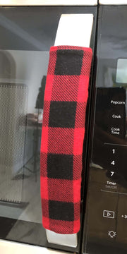 Red and black buffalo check appliance handle covers on a microwave, adding rustic charm to kitchen decor.
