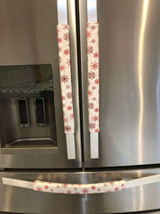 Rose pink snowflake appliance handle covers on refrigerator handles, adding a festive touch to kitchen decor.