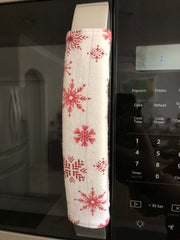 Rose pink snowflake appliance handle covers on a microwave, adding a festive touch to kitchen decor.