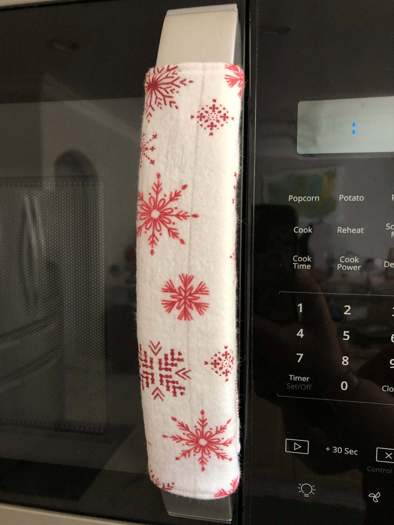 Rose pink snowflake appliance handle covers on a microwave, adding a festive touch to kitchen decor.