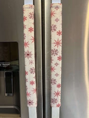 Rose pink snowflake appliance handle covers on refrigerator handles, adding a festive touch to kitchen decor.