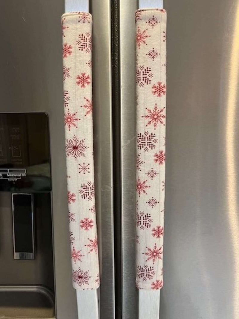 Rose pink snowflake appliance handle covers on refrigerator handles, adding a festive touch to kitchen decor.
