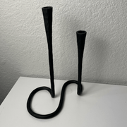 Black metal candle holder on a white surface with a plain background