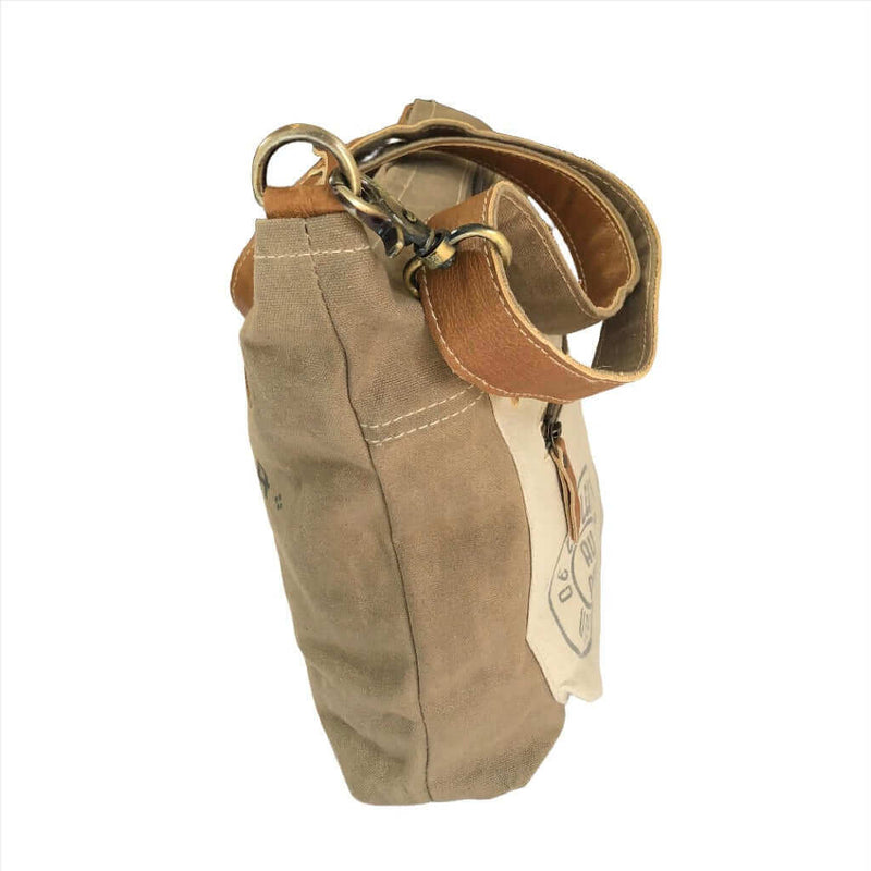 Upcycled canvas shoulder bag with adjustable leather straps and zipper pocket, eco-friendly, quirky design.