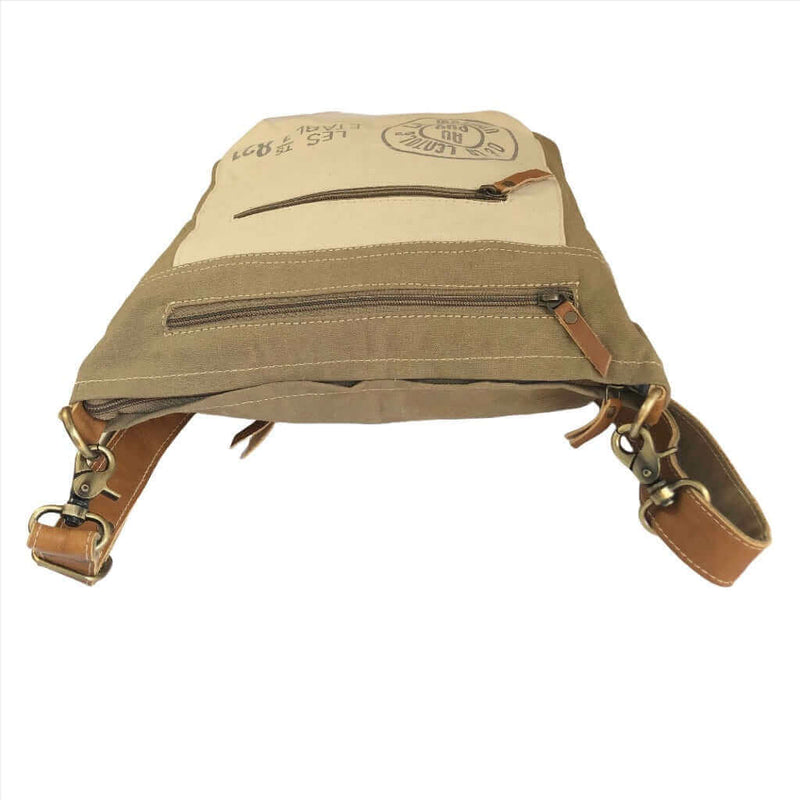 Upcycled canvas shoulder bag with adjustable leather straps and zippered pockets, eco-friendly accessory.