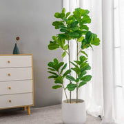Large realistic artificial ficus tree in a modern interior setting with a white pot and natural light.